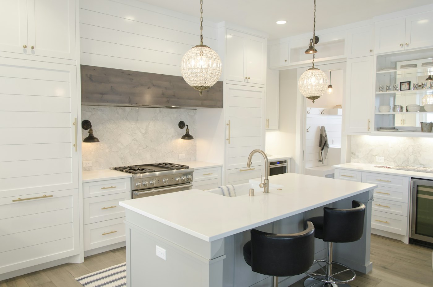 Bright kitchen with white shaker cabinets, a marble-look island and pendant lights