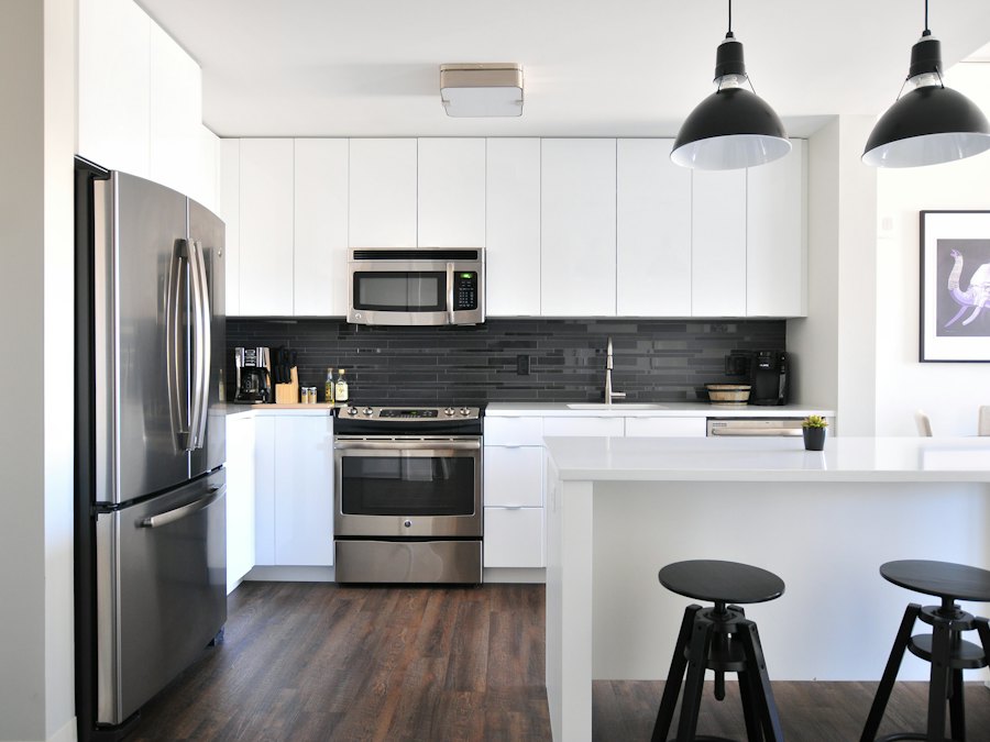 Modern white kitchen with dark backsplash and stainless appliances